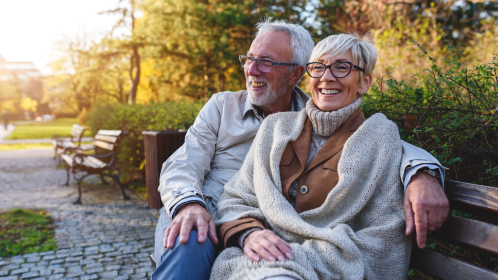 Adobe Stock - Senior couple smiling on a bench during the Fall.